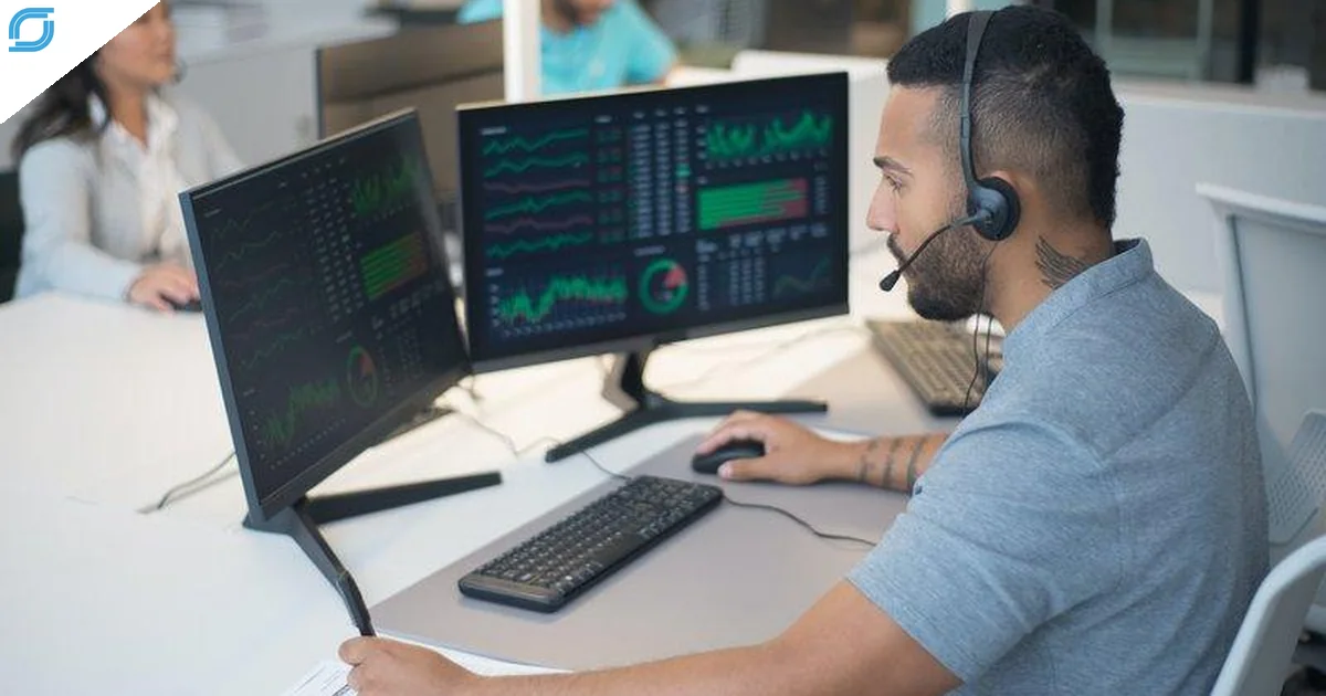 Telecom billing support agent reviewing billing and performance dashboards on dual monitors while assisting customers.