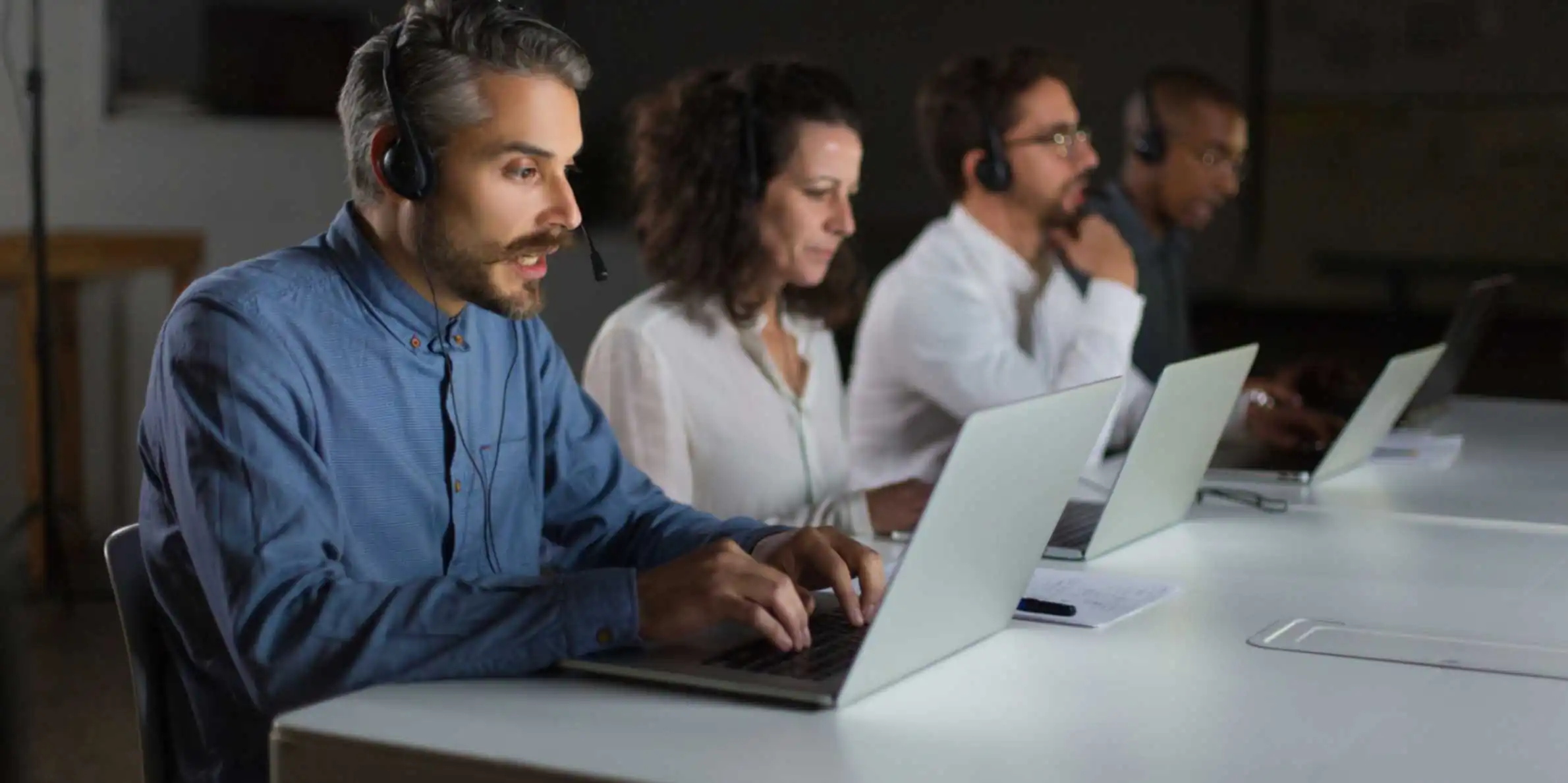 Challenges in telecom order management illustrated by a customer support team handling service requests on laptops in a call center office
