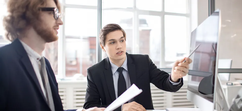 Telecom data center compliance analyst reviewing weekly documentation with a colleague on screen